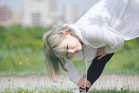 Asian young woman doing stretching exercise in urban green spaceの写真素材