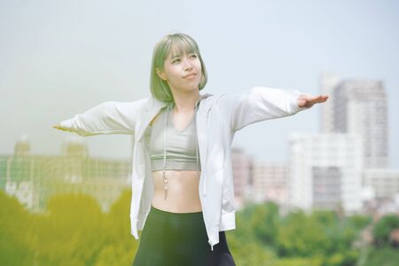 Asian young woman doing stretching exercise in urban green space