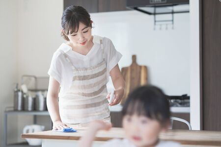 Asian woman cleaning home dining table with sanitizer spray and rag