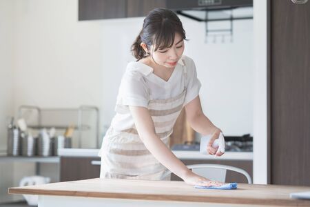 Asian woman cleaning home dining table with sanitizer spray and ragの写真素材