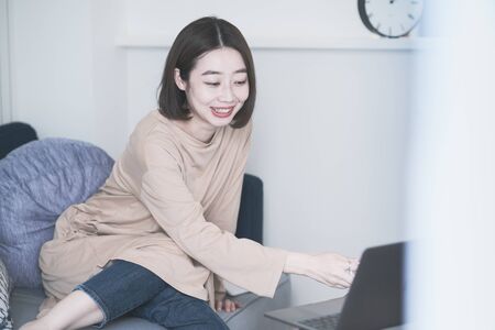 Asian young woman looking at laptop screen in the room at homeの写真素材