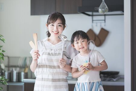 Asian young mom and daughter challenge cooking with kitchen toolsの写真素材