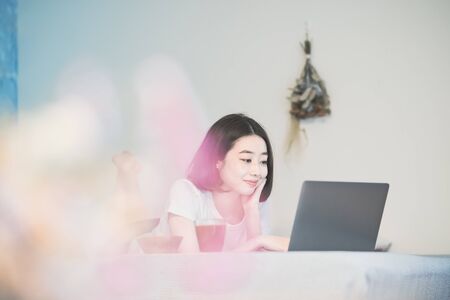 Asian young woman looking at laptop screen in the room at homeの写真素材