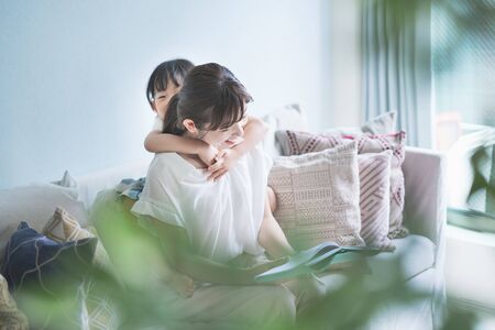 Mother and daughter sitting on the sofa and reading a picture book
