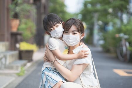 Asian mom and daughter wearing masks and going out on a sunny dayの写真素材