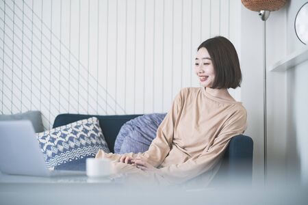 Asian young woman looking at laptop screen in the room at homeの写真素材