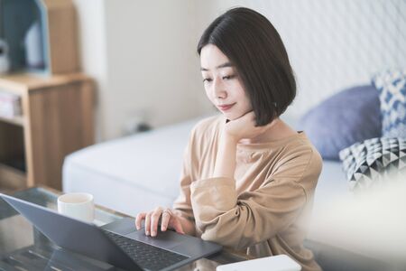 Asian young woman working remotely with laptop in room at homeの写真素材