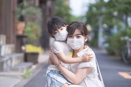 Asian mom and daughter wearing masks and going out on a sunny dayの写真素材