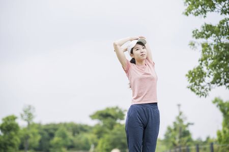 Asian young woman wearing sportswear and exercising in the parkの写真素材