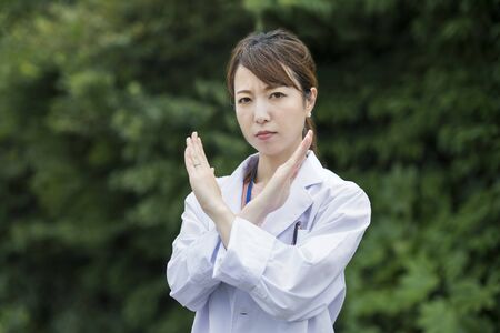 Asian female healthcare worker in white coat posing for refusal/mistakeの写真素材