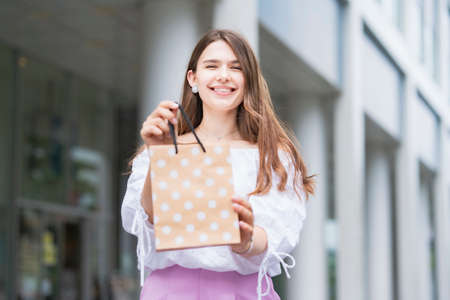 Young woman holding a paper bag with presents with a smileの写真素材