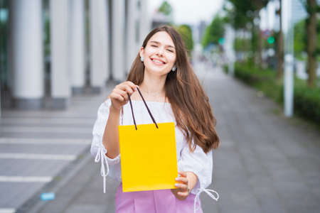 Young woman holding a paper bag with presents with a smileの写真素材