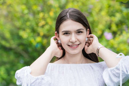 A young woman wearing a white off-shoulder shirt and surrounded by plantsの写真素材