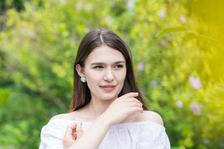 A young woman wearing a white off-shoulder shirt and surrounded by plantsの写真素材