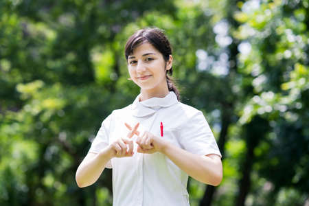 Outdoor portrait of young woman posing in white coat on fine dayの写真素材