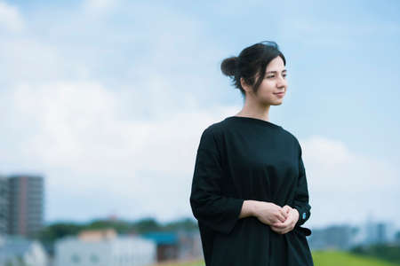 A young woman showing a relaxed expression under the blue skyの写真素材