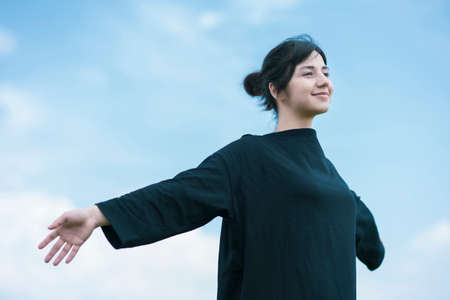 A young woman showing a relaxed expression under the blue skyの写真素材