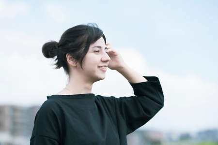 A young woman showing a relaxed expression under the blue skyの写真素材