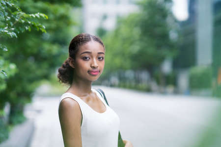 Young business woman in sleeveless white tops in a green city