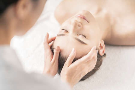 Young woman having her head massaged at the beauty salonの写真素材