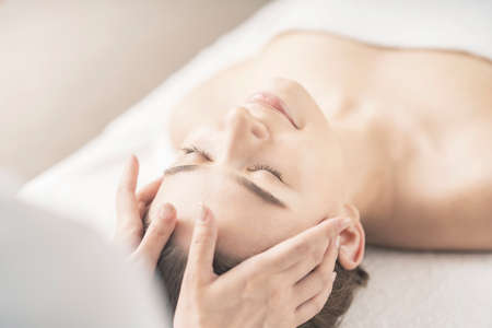 Young woman having her head massaged at the beauty salonの写真素材