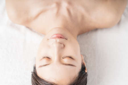 Relaxed face of young woman lying down in beauty salonの写真素材