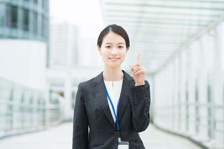 Portrait of Asian young business woman posing with pointing fingerの写真素材