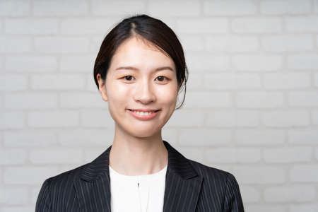 Portrait of a smiling Asian young business woman wearing a suitの写真素材