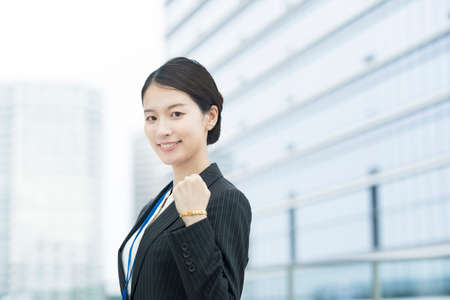 Asian young business woman in a suit posing with a smile and cheeringの写真素材