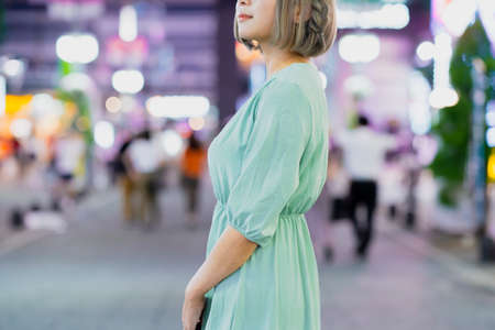 Young woman posing in the glowing cityscape of Tokyo at nightの写真素材