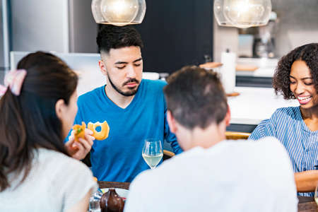 Scene of a home party where men and women surround the dining table