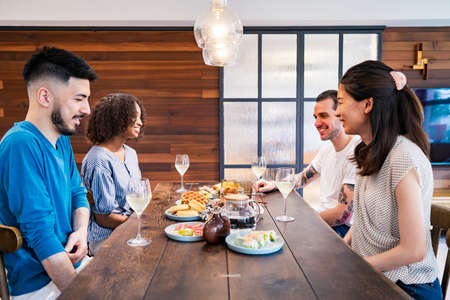 Scene of a home party where men and women surround the dining tableの写真素材
