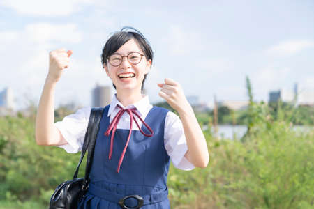 A female high school student posing cheering with a smile outdoors