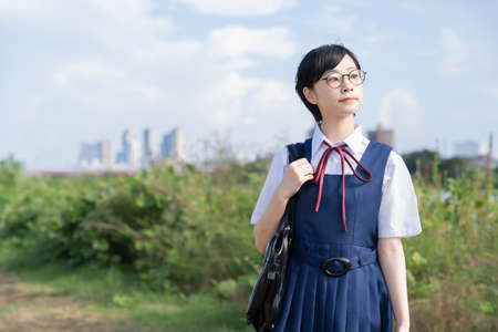 asian high school girl with glasses looking up at the skyの写真素材