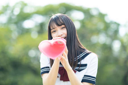 asian high school girl cheering with a heart shaped megaphoneの写真素材