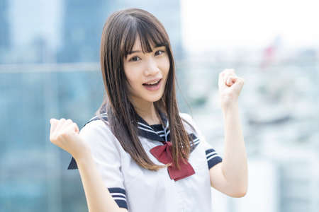 A female high school student posing supporting with a smile outdoorsの写真素材