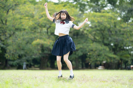 Asian female high school student frolicking with a smile in the parkの写真素材