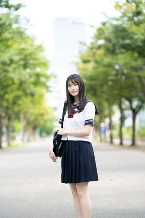 asian female high school student smiling in uniform outdoorsの写真素材