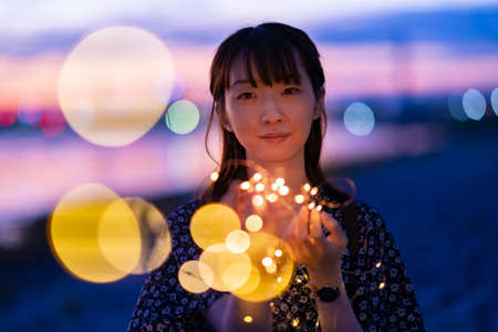 Asian young woman staring at the illumination lights in evening timeの写真素材
