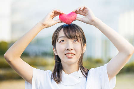 A woman in a white coat with a heart-shaped accessoryの写真素材