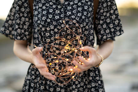 Asian young woman wrapping an illumination light with both hands