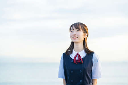 High school girl showing a smile and the background of the seaの写真素材