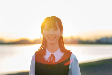Asian female high school student wrapped in the setting sunの写真素材