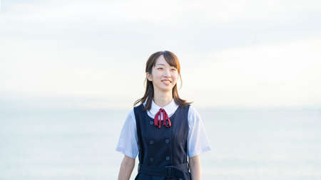 High school girl showing a smile and the background of the seaの写真素材