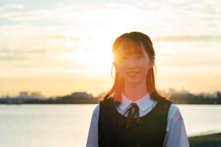 Asian female high school student wrapped in the setting sunの写真素材