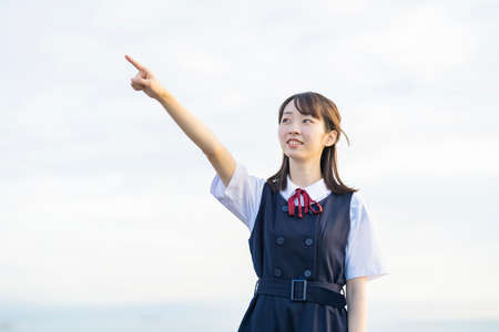 Asian female high school student pointing at the skyの写真素材