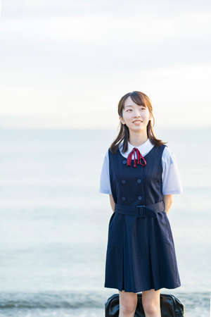 High school girl showing a smile and the background of the seaの写真素材