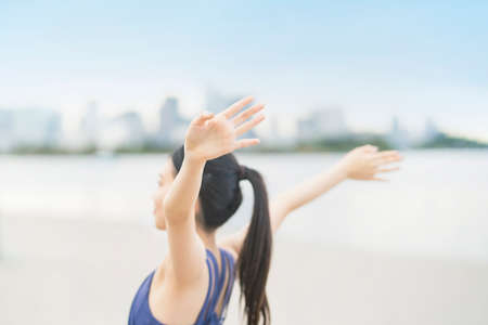 Young woman stretching and taking a deep breath on the beach of the cityの写真素材