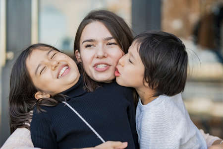 Mom and 2 kids frolicking with a smile outdoors