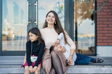 Mom and 2 kids frolicking with a smile outdoors